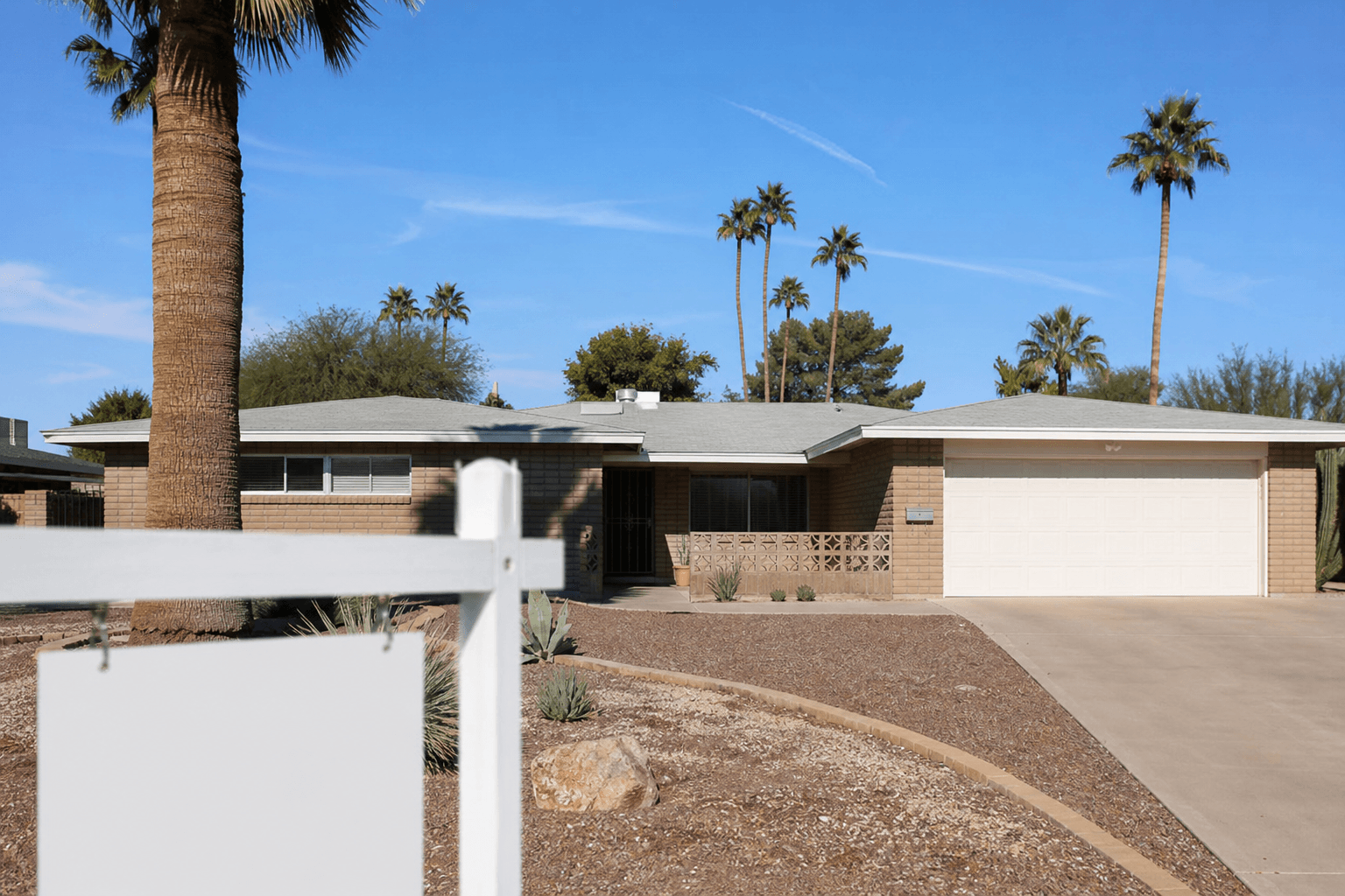 Las Vegas ranch-style home with a yard sign in soft focus on a sunny desert day